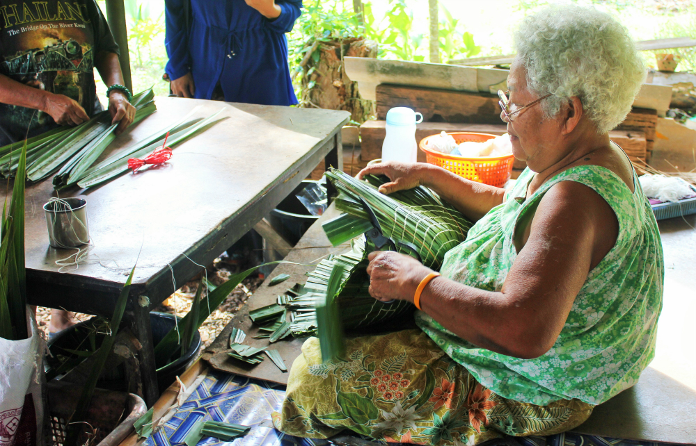 A woman weaving leaves to make an eco-friendly basket